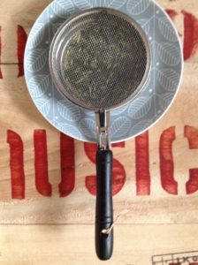 ムジカティーの木箱の上のお皿の上にのったゴマ炒り器