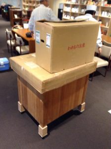 小型焙炉の上部に段ボールで蓋をして、その上に荷物をまとめた段ボールを置いてます。